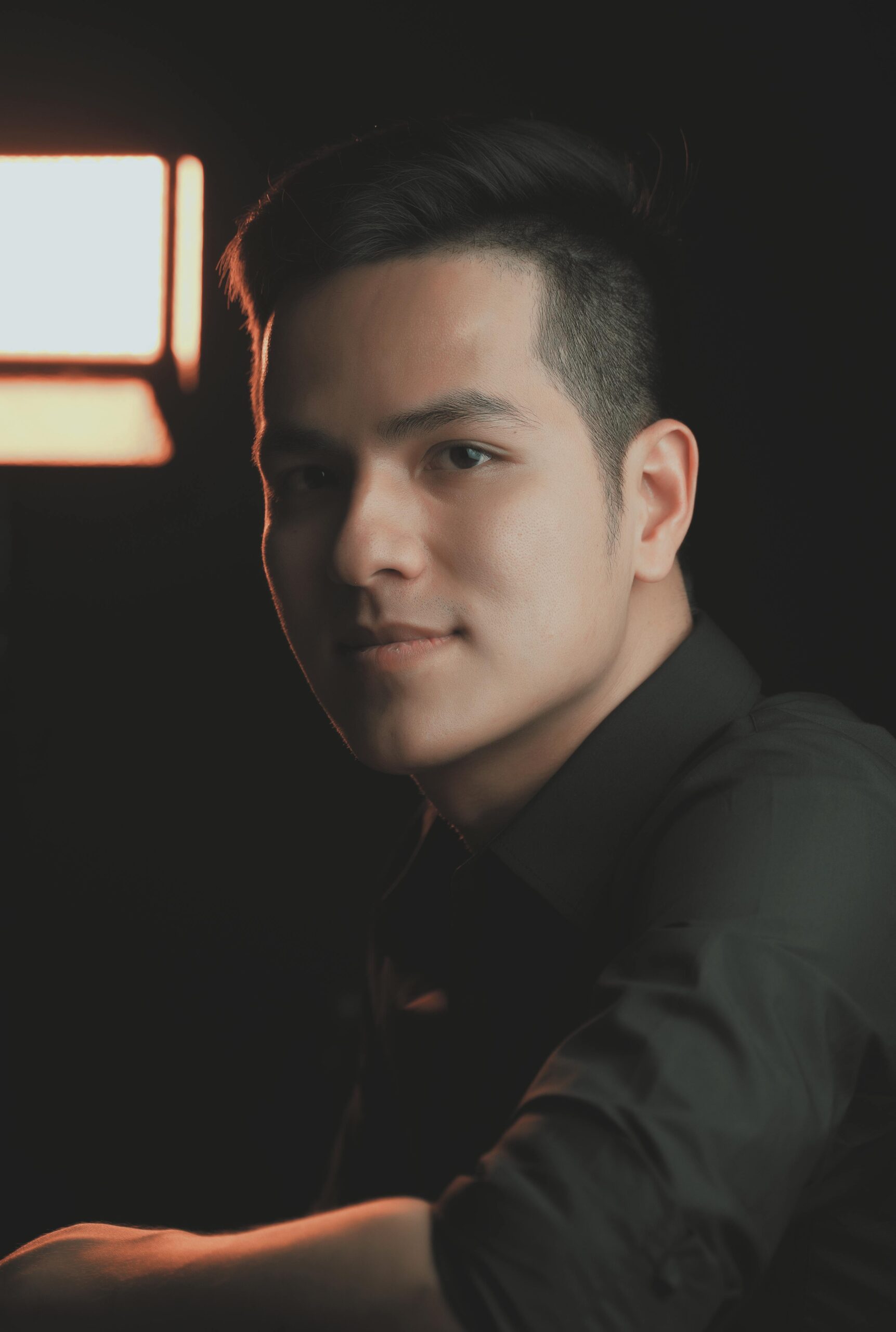 Close-up portrait of a young man in soft lighting, creating a moody atmosphere.