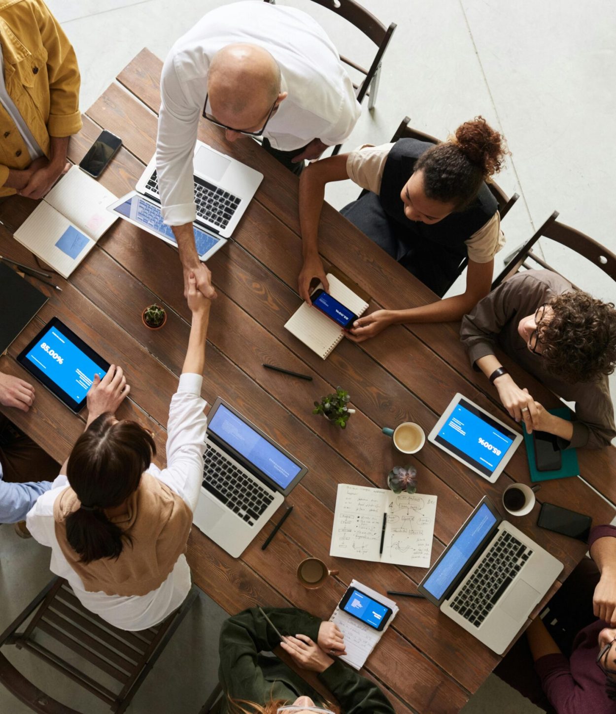 pexels-photo-3183197-3183197 Top view of a diverse team collaborating in an office setting with laptops and tablets, promoting cooperation.